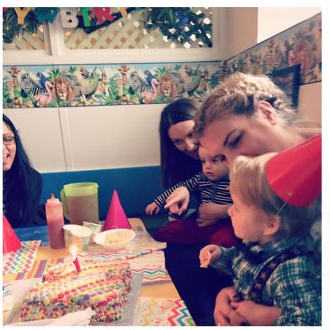 Family gathered around a birthday cake at a party table