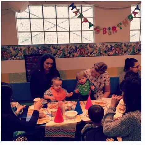 Toddlers in party bibs at a decorated table with their parents